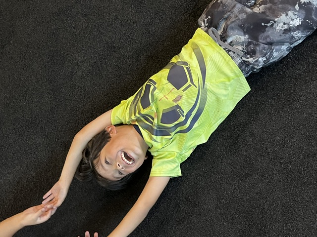 Happy kid laughing on gym floor at Power Play PE Sacramento preschool class