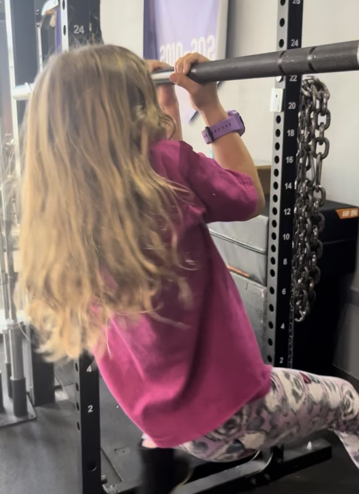 Young girl doing dead hang on pull-up bar at Power Play PE Sacramento gym