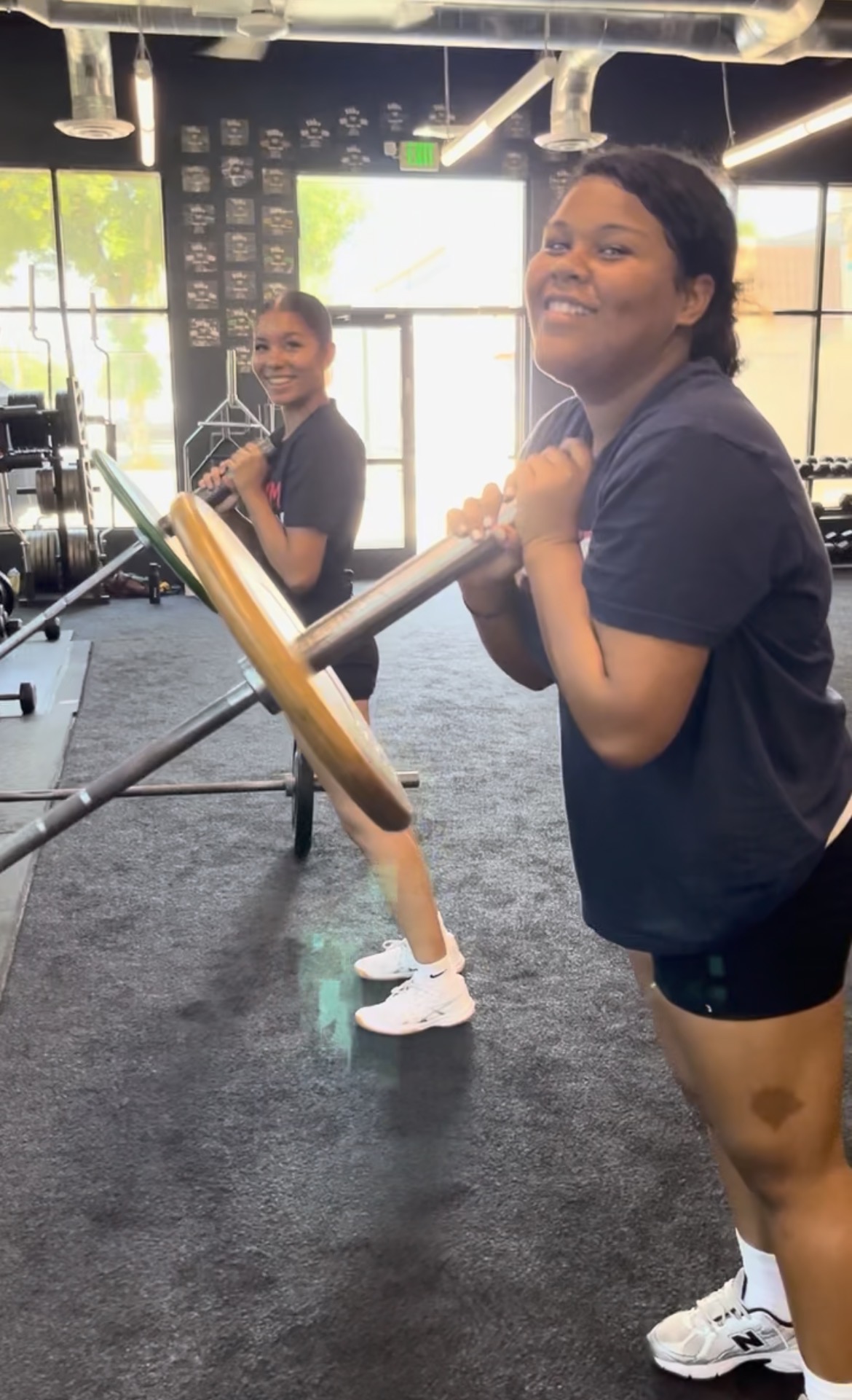 Teen girls doing barbell rows smiling at Power Play PE Sacramento