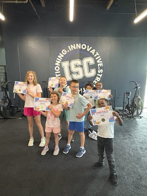 Power Play PE kids holding certificates in front of ISC logo wall Sacramento homeschool PE