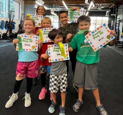 Kids proudly holding certificates after homeschool PE session at Power Play Sacramento