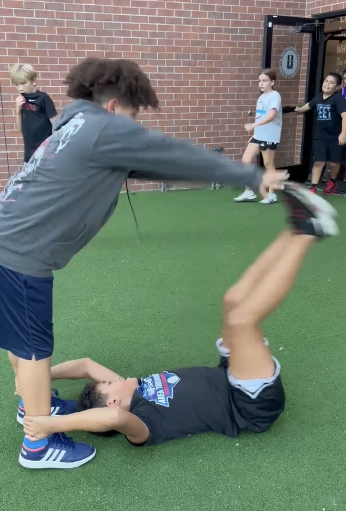 Teens doing partner leg raises on turf at Power Play PE Sacramento